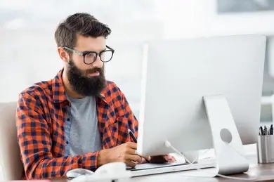 Image de hipster pensif, derrière son écran d'ordinateur.